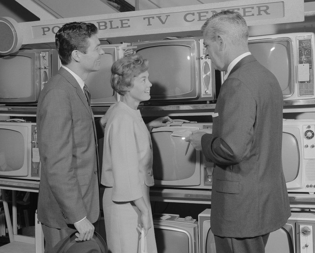 Detail of Couple shopping for portable tv being helped by salesman by Anonymous