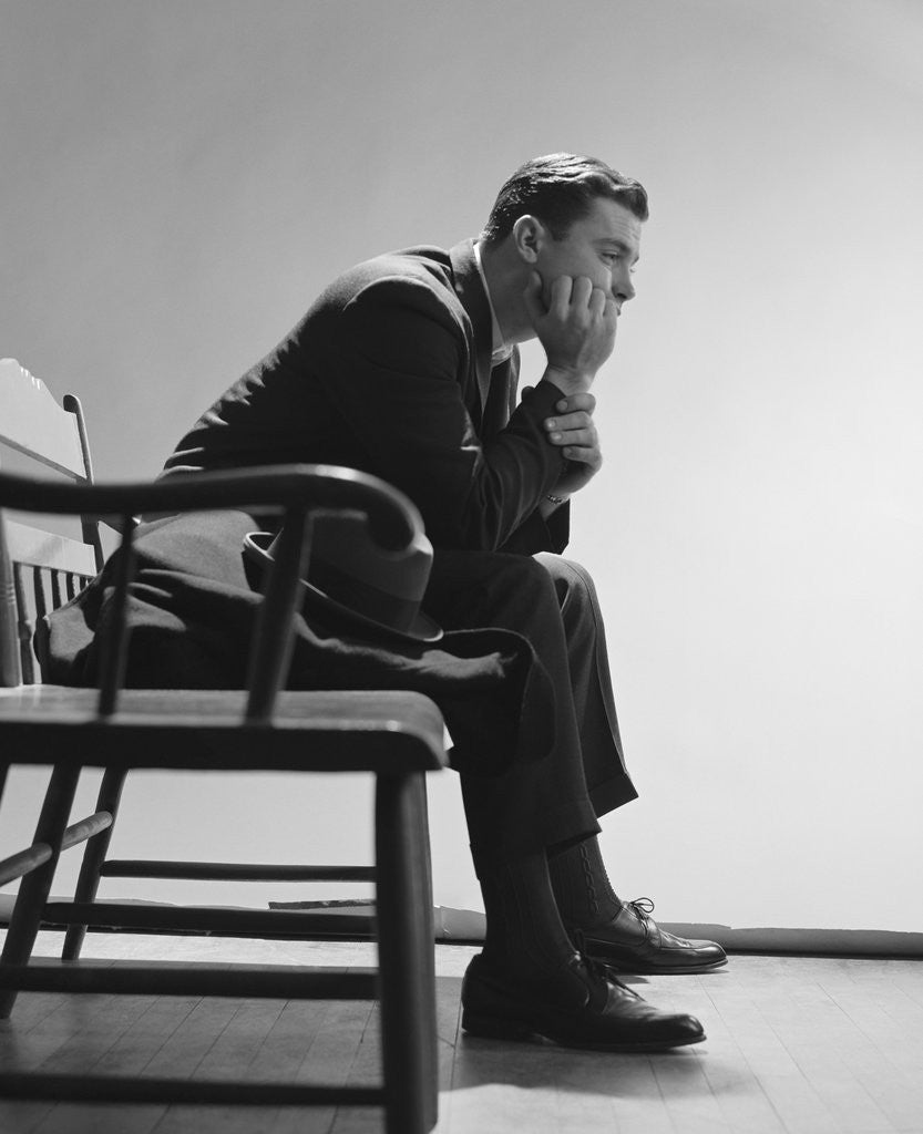 Detail of Sad man resting hand on chin sitting on bench by Anonymous