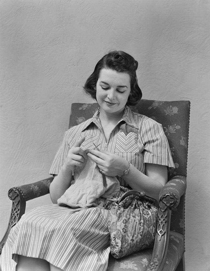 Detail of Brunette woman knitting sitting in armchair by Anonymous