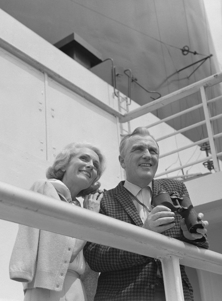 Detail of Smiling mature couple at shipboard rail with binoculars by Anonymous