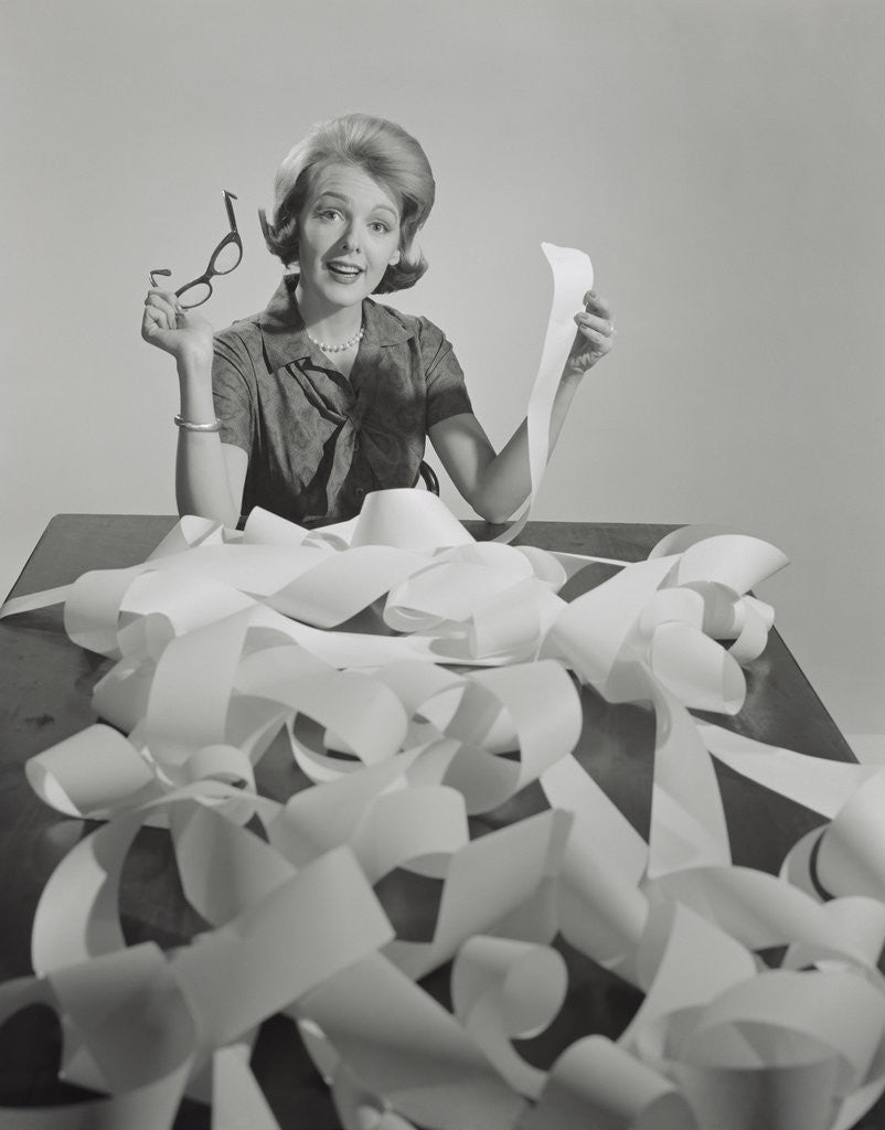Detail of Woman holding eyeglasses and end of extremely long tape from office machine by Anonymous