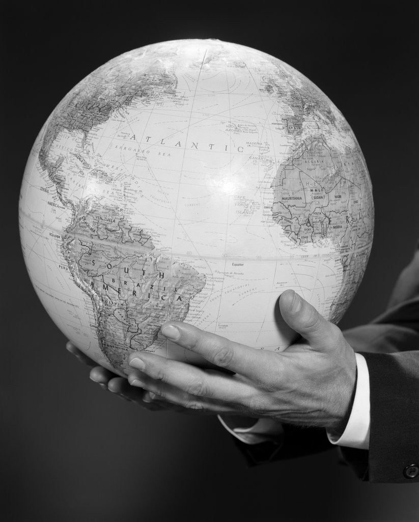 Detail of Mans hand holding globe of the world by Corbis