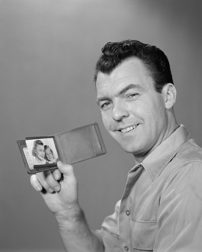 Detail of Smiling man holding up wallet with picture of wife and daughter by Anonymous