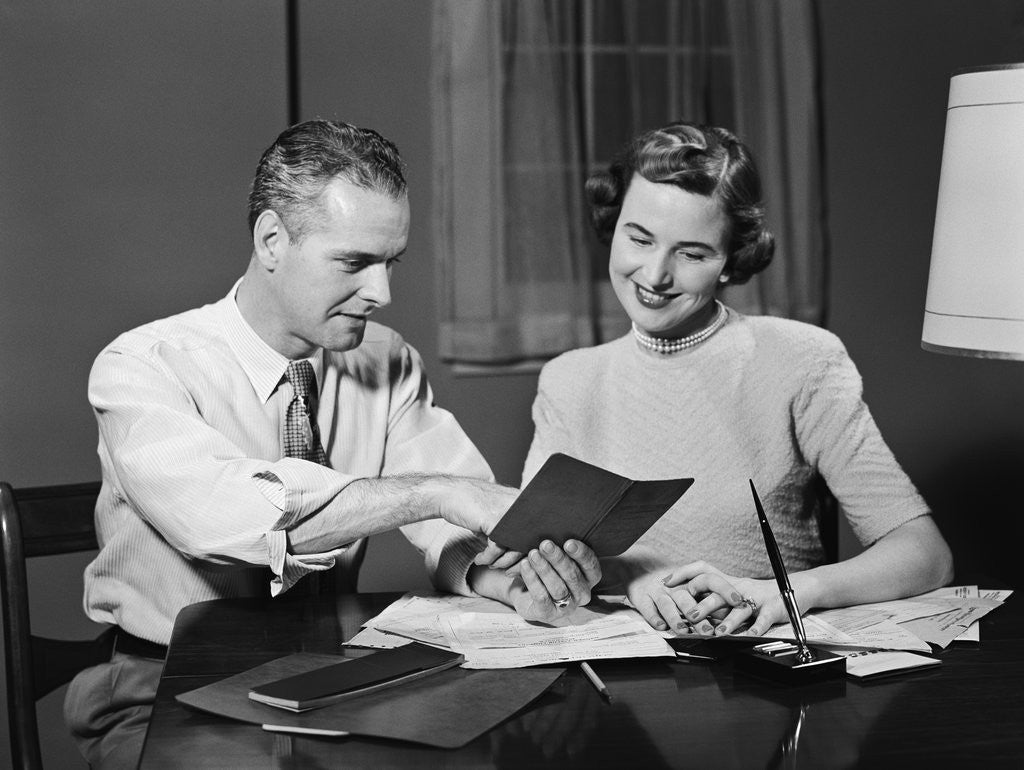 Detail of Couple man woman smiling looking at banking savings passbook at home desk by Anonymous