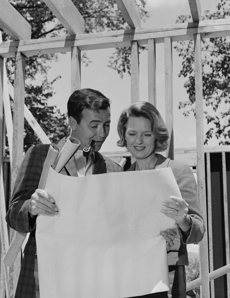Detail of Couple looking at house plans blueprints man smoking pipe by Anonymous