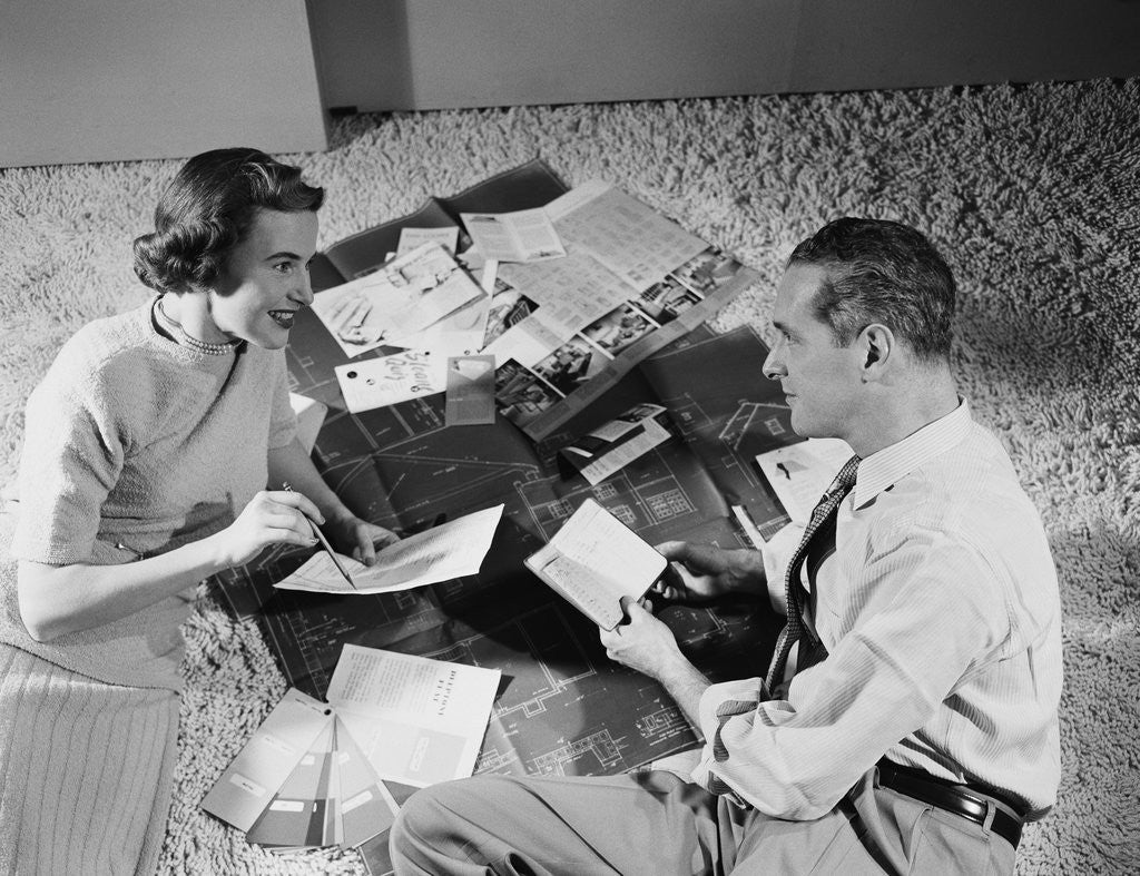 Detail of Couple man woman sitting floor looking at plans for new house by Anonymous