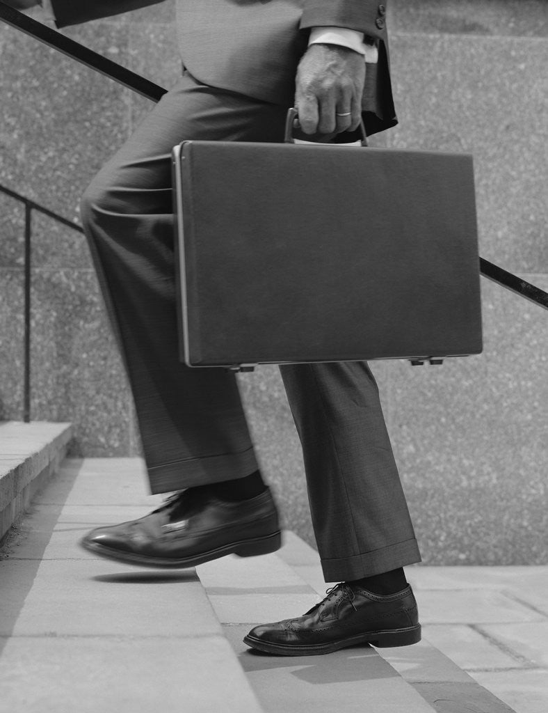 Detail of Businessman legs walking up stairs hand holding briefcase by Anonymous