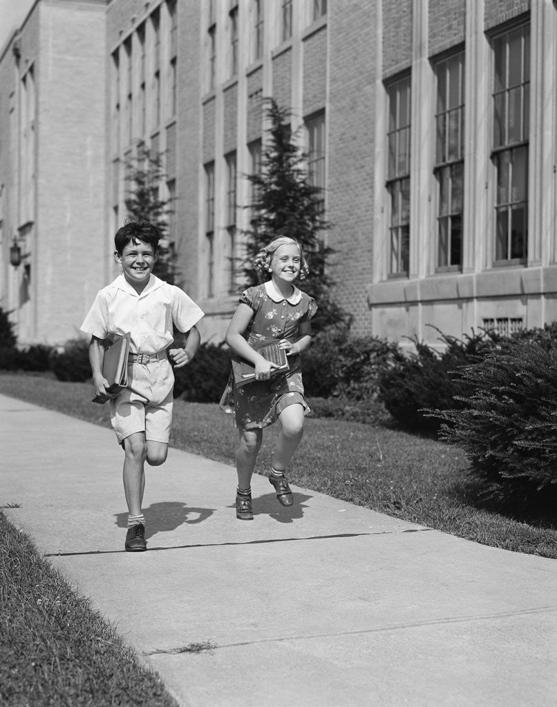 Detail of Boy girl running down sidewalk carrying school books smiling by Anonymous