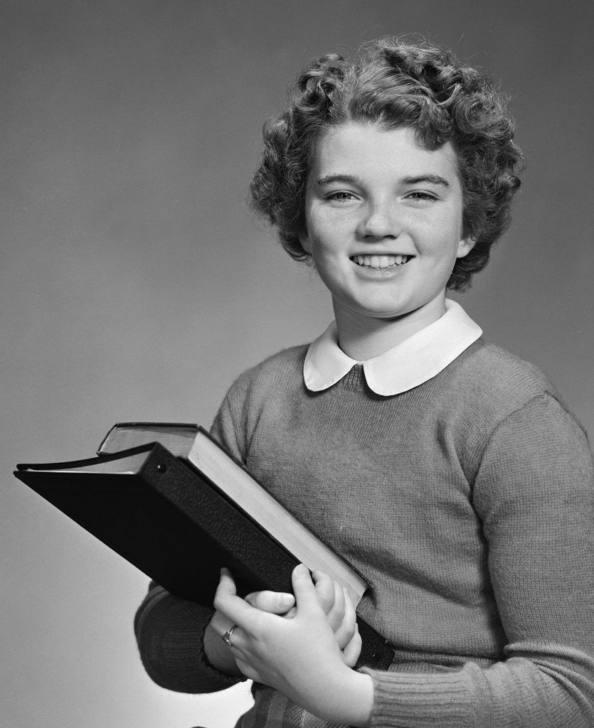 Detail of Adolescent teen girl smiling portrait holding school books by Corbis