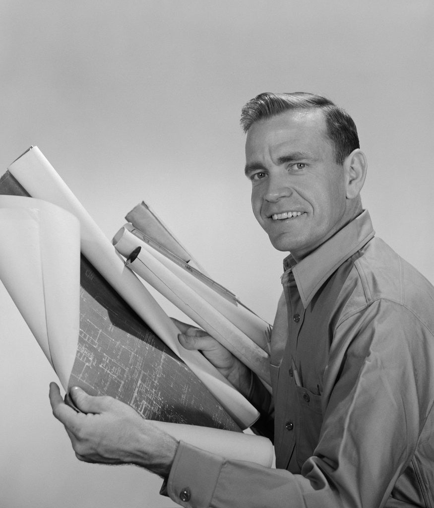 Detail of Smiling man builder contractor holding blueprints looking at camera by Anonymous
