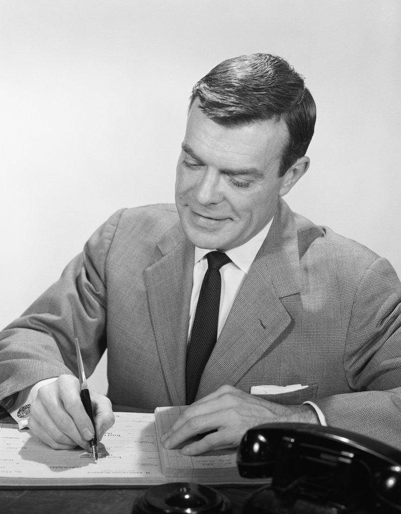 Detail of Smiling businessman at desk writing checks by Anonymous