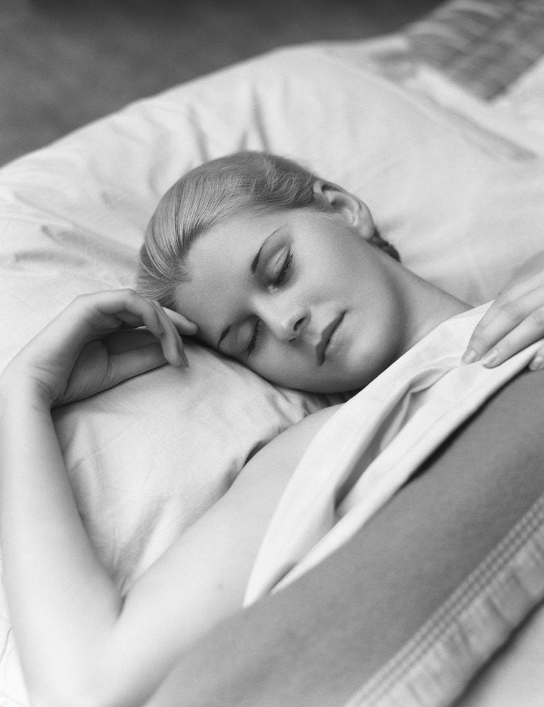 Detail of Sleeping blond woman eyes closed head resting on pillow in bed by Anonymous