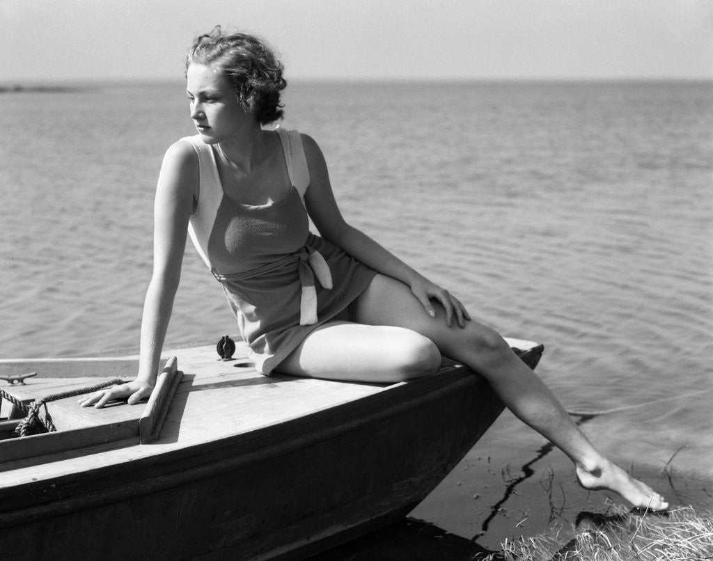 Detail of Woman wearing one piece bathing suit sitting on edge of boat by Anonymous
