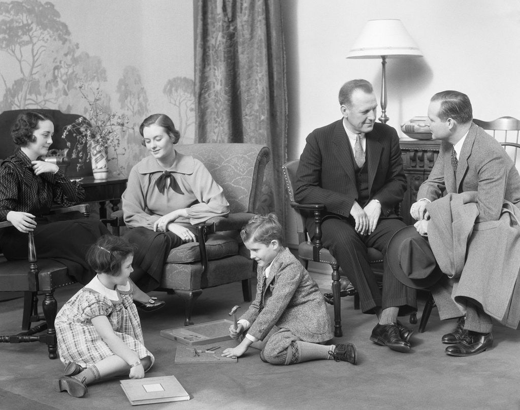 Detail of Family mother father two kids playing on floor visiting with another couple by Anonymous