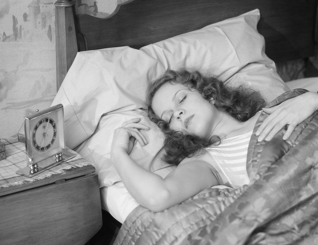Detail of Woman sleeping asleep in bed alarm clock on night table by Anonymous