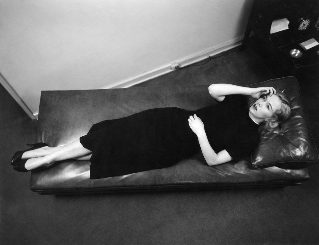 Detail of Worried woman hand to forehead seen from above lying down on psychiatrist therapy couch by Anonymous