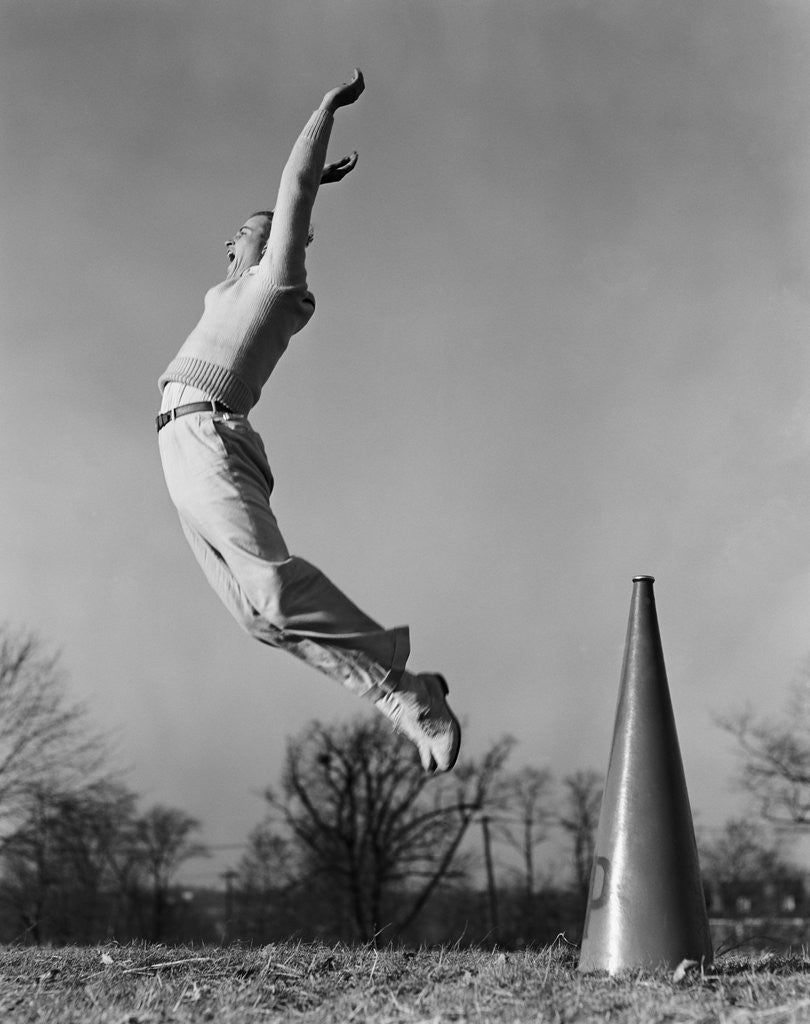 Detail of Male cheerleader jumping cheering megaphone on ground by Anonymous