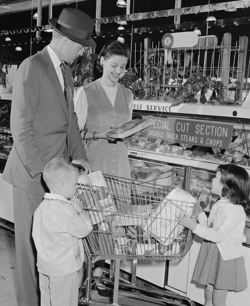 Detail of Family of 4 inside supermarket father pushing cart mother 2 kids by Anonymous