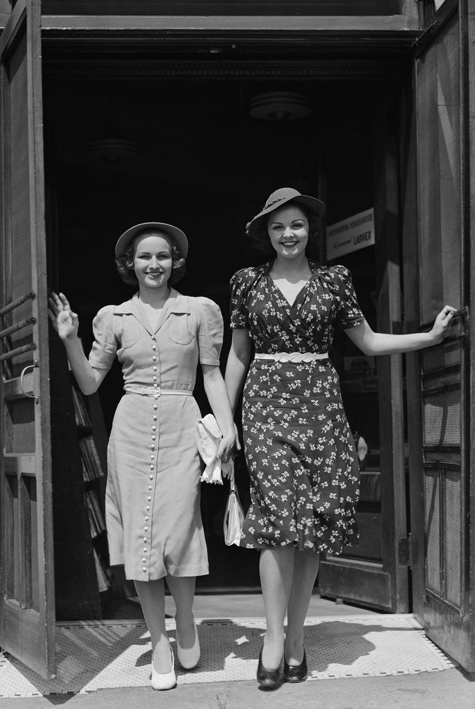 Detail of Two smiling women walking out doorway of a store by Corbis