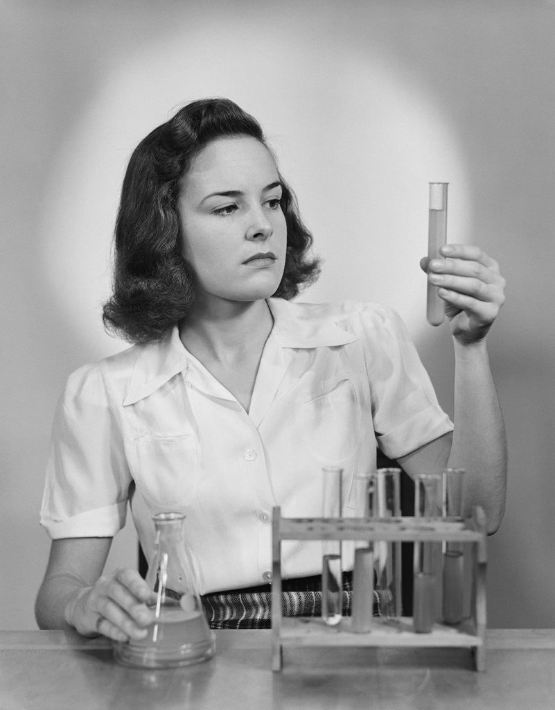 Detail of Young woman chemist holding up test tube by Anonymous