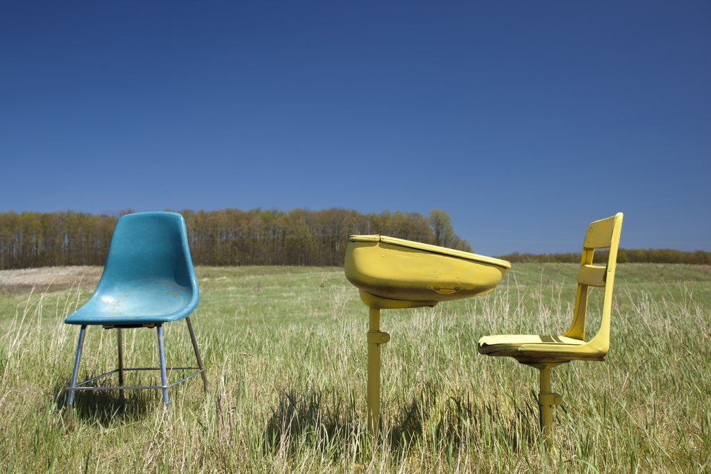 Detail of Abandoned school desk anc chairs in field by Anonymous
