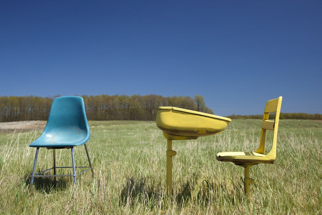 Detail of Abandoned school desk anc chairs in field by Corbis