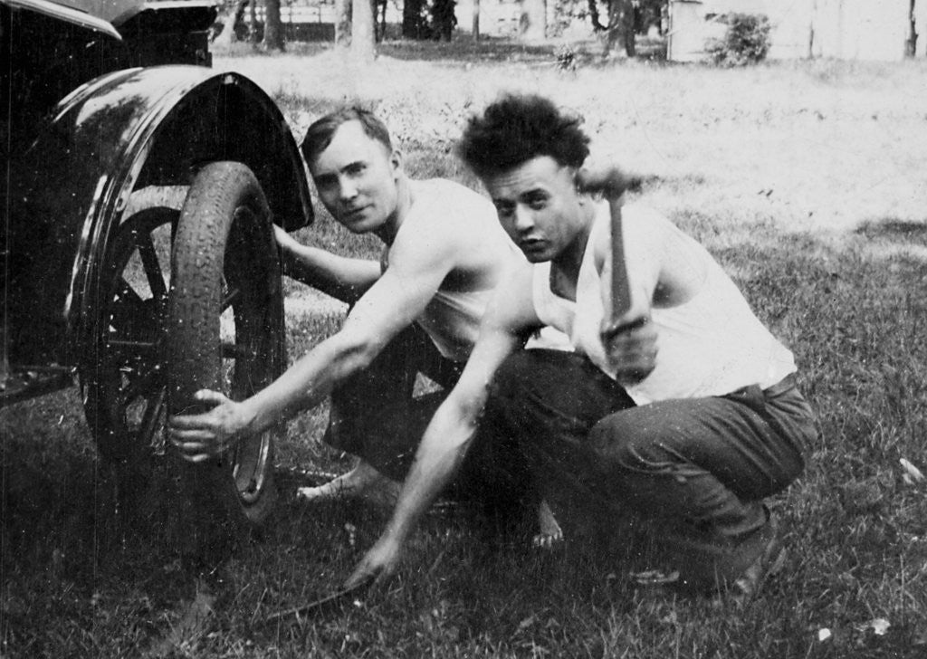 Detail of Young men change a tire on an automobile, ca. 1918 by Corbis