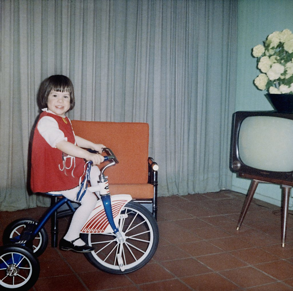 Detail of Young girl rides her new tricycle in the house, ca. 1967 by Anonymous