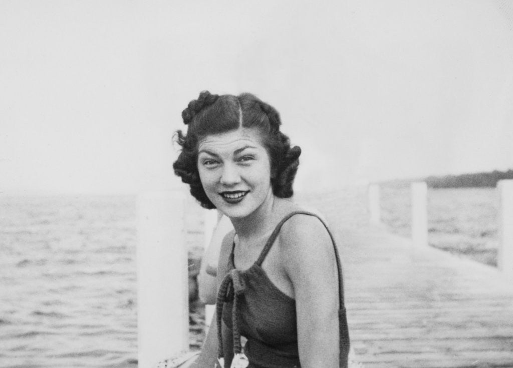 Detail of Young woman smiles and sits on a swimming pier, ca. 1938. by Anonymous