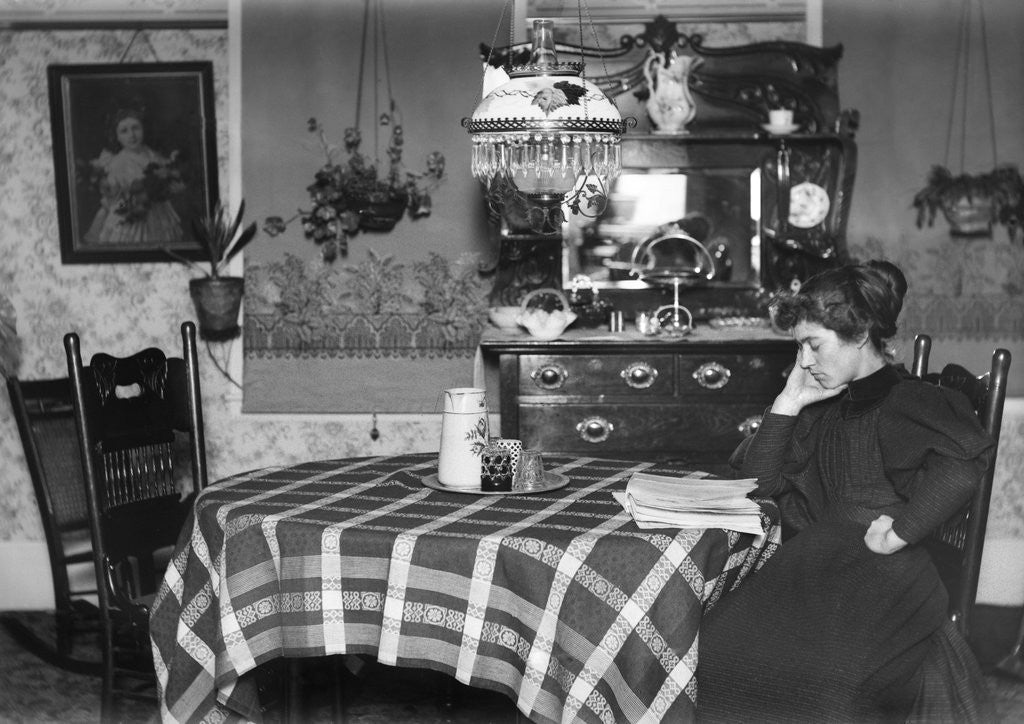 Detail of A woman reads at the dining table, ca. 1900. by Anonymous