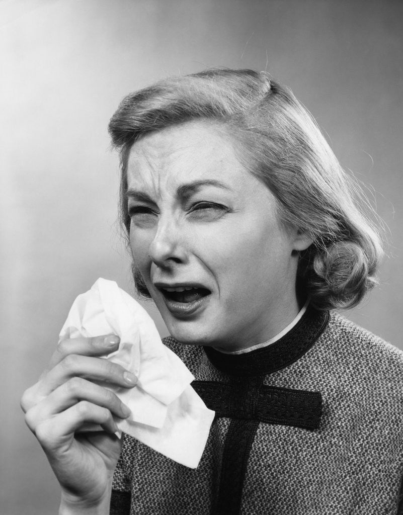 Detail of 1950s woman with handkerchief sneezing indoor by Anonymous