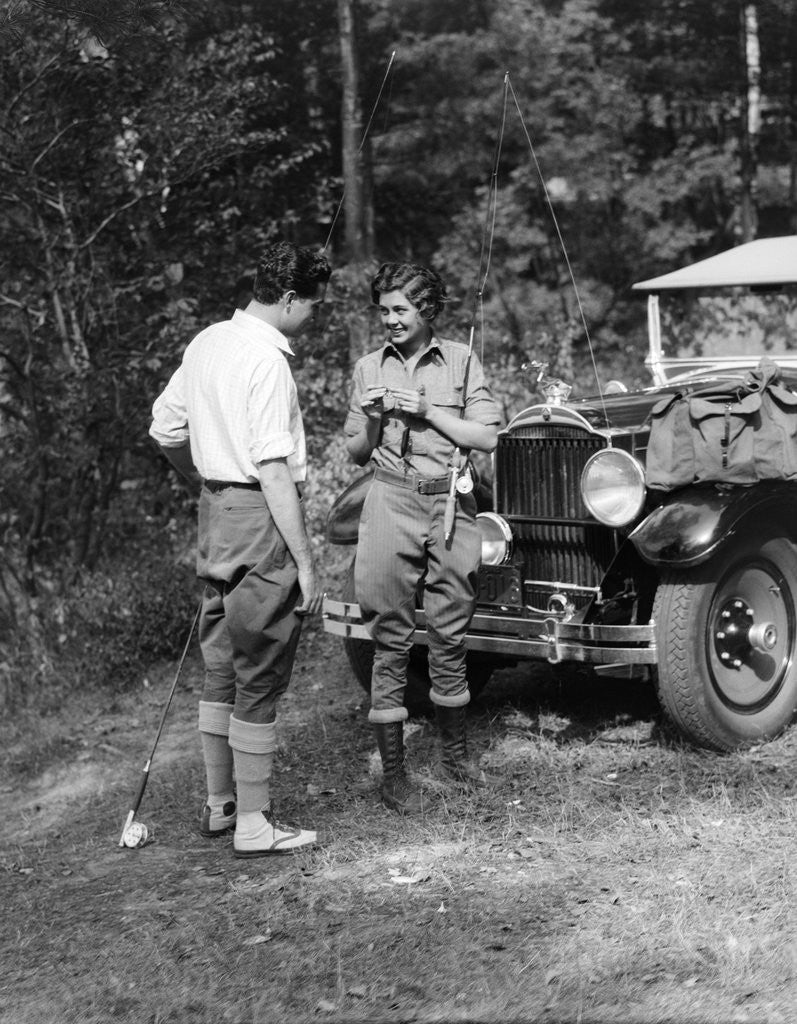Detail of 1920s 1930s couple man woman in fishing gear holding poles standing in front of packard touring automobile by Anonymous