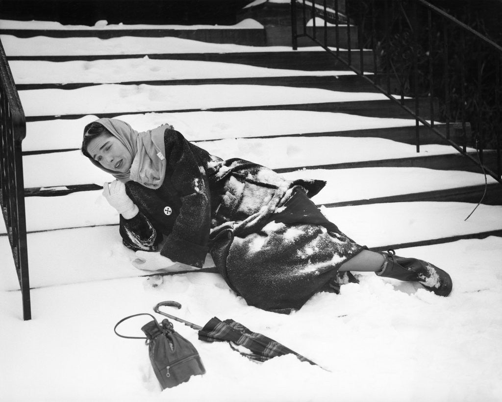 Detail of 1950s woman lying on snow covered steps fall accident slip expression of pain by Anonymous