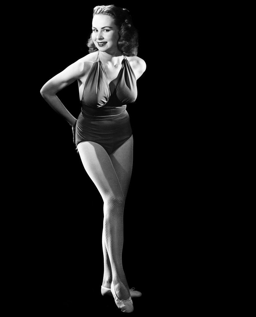 Detail of 1950s busty young woman posing standing inside wearing bathing suit looking at camera by Anonymous