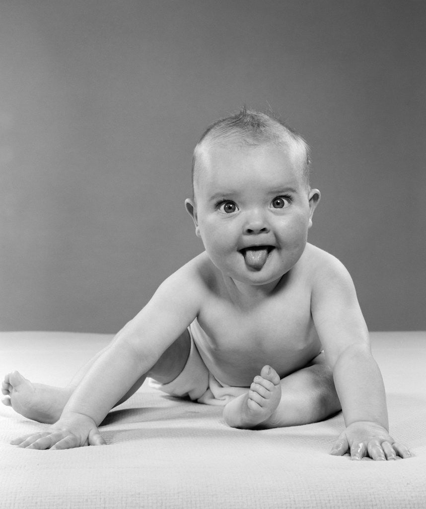 Detail of 1950s portrait of baby sitting and sticking tongue out looking at camera by Anonymous