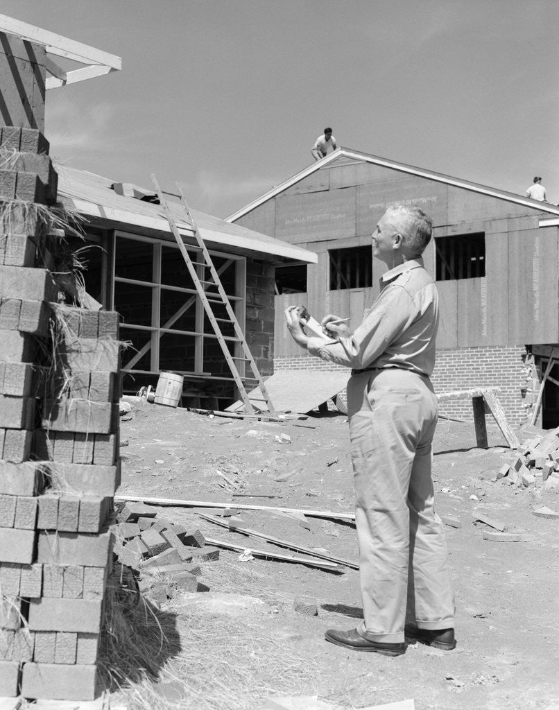 Detail of 1950s senior man with clipboard on construction site by Anonymous