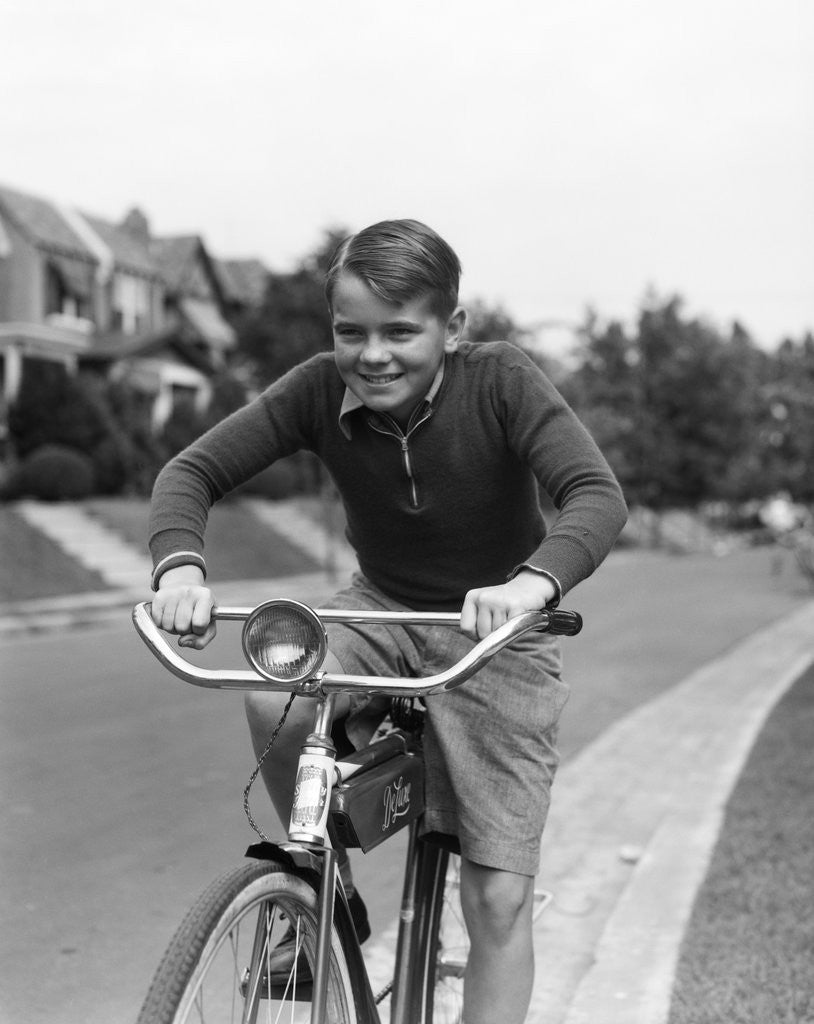 Detail of 1930s smiling boy riding bicycle by Corbis