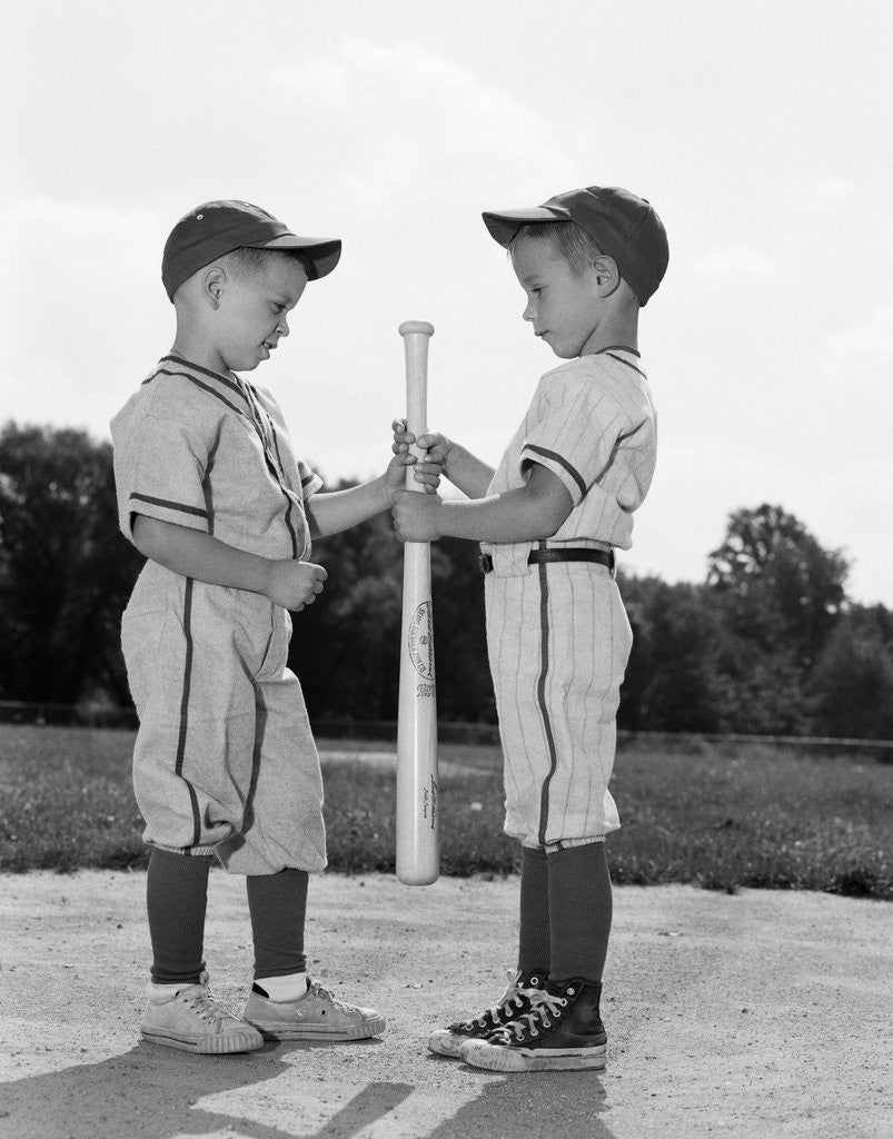 Detail of 1960s two boys in baseball uniforms choosing sides by getting the upper hand on a bat by Corbis