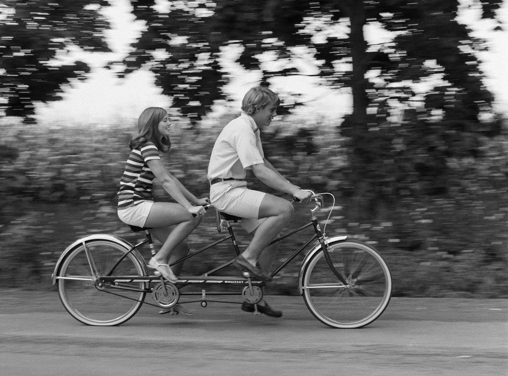 Detail of 1970s teenage girl and boy riding bicycle built for two by Anonymous