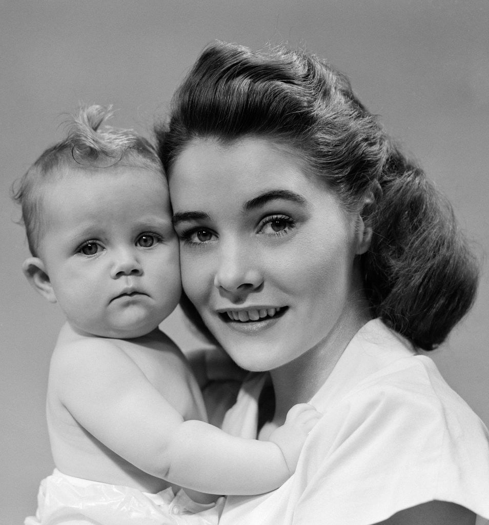 Detail of 1940s 1950s portrait of mother hugging baby looking at camera by Corbis