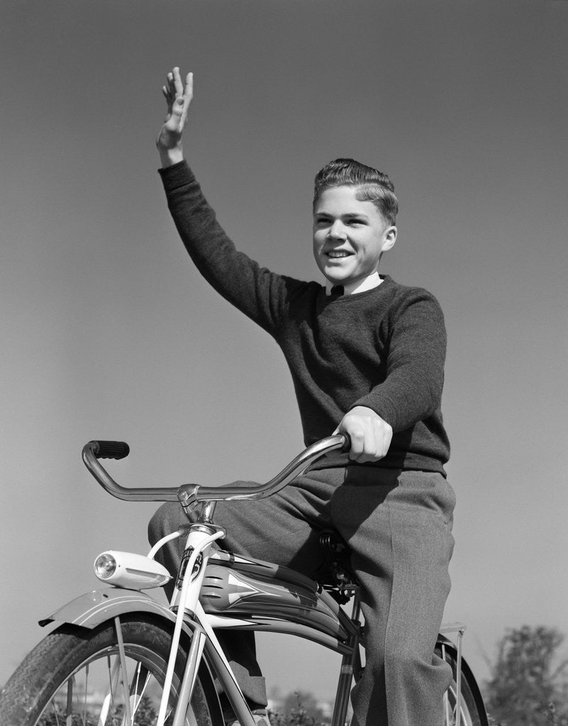 Detail of 1940s 1950s smiling boy riding bike waving arm in air by Corbis