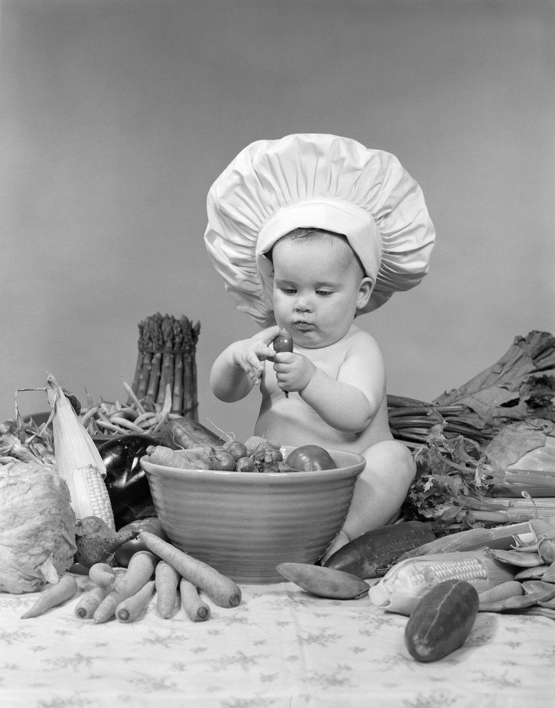 Detail of 1950s 1960s baby wearing chef hat toque bowl and raw vegetables making a salad by Anonymous