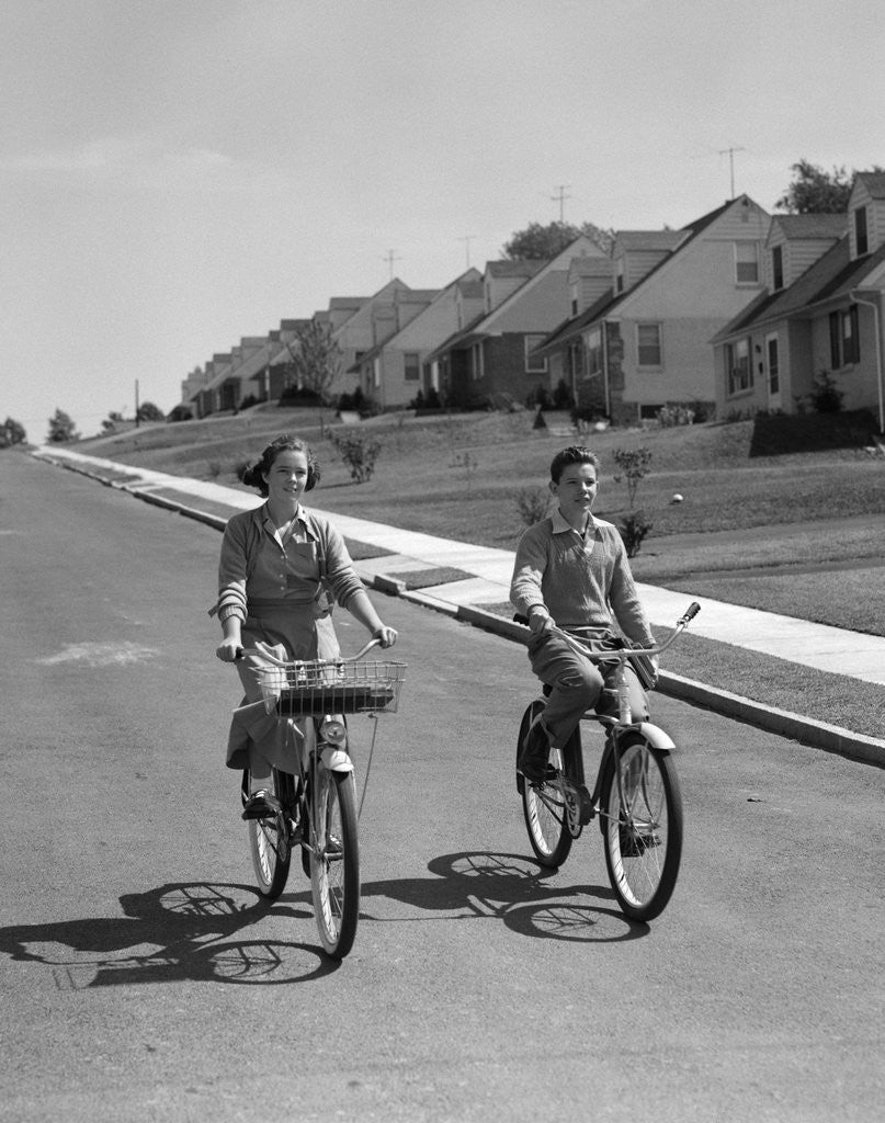 Detail of 1950s teen boy girl riding bikes suburban neighborhood street by Anonymous