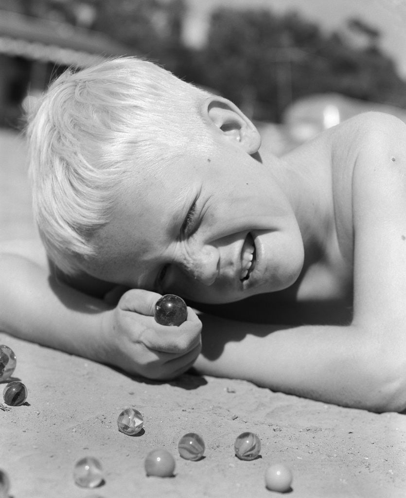 Detail of Boy crouching shooting marbles concentration by Anonymous