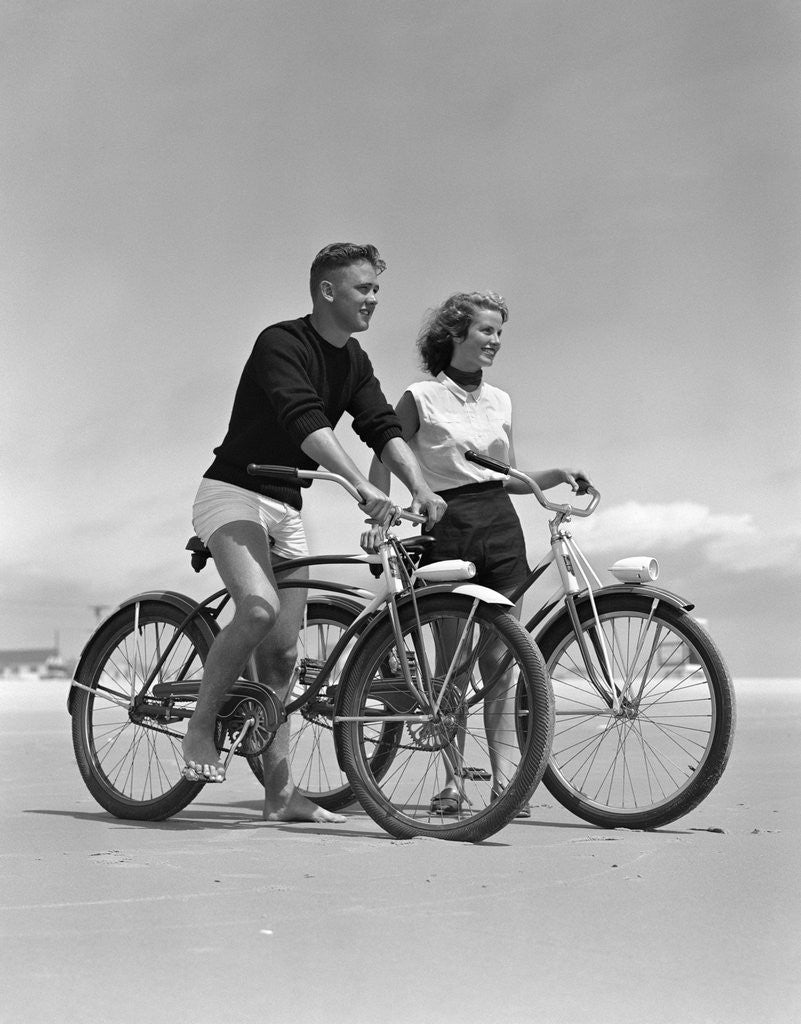 Detail of 1950s teenage boy and girl with bikes on the beach by Corbis
