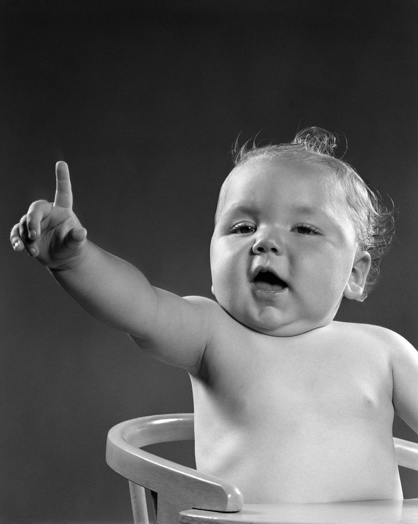 Detail of 1940s 1950s baby sitting in chair arm and one finger raised objecting voting making a point looking at camera by Anonymous