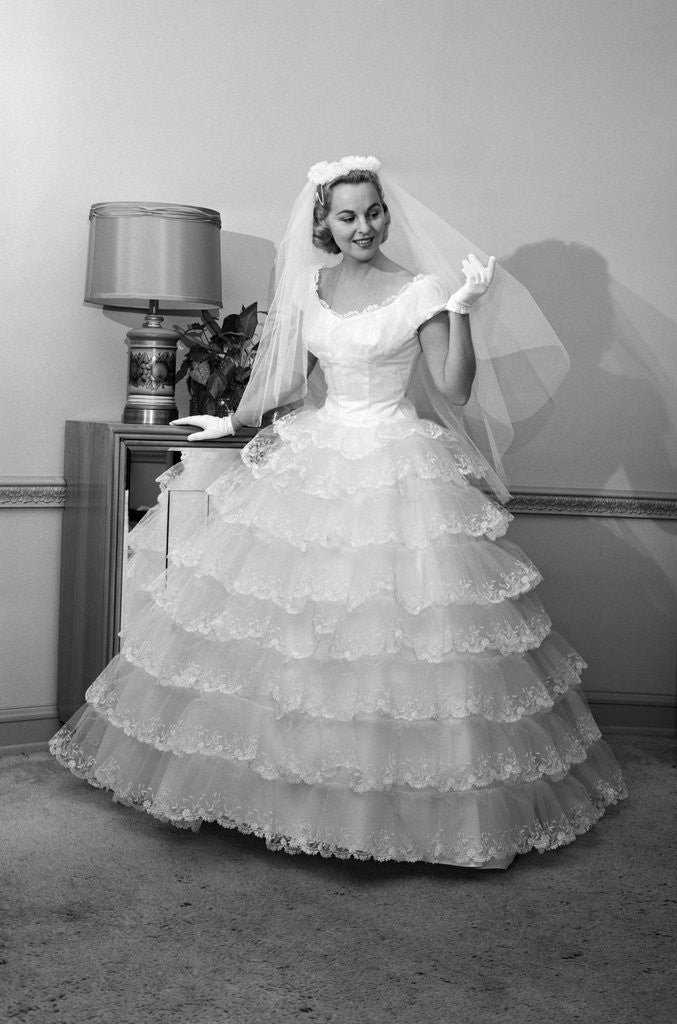 Detail of 1950s 1960s bride in full gown veil & white gloves standing in room with open door by Corbis