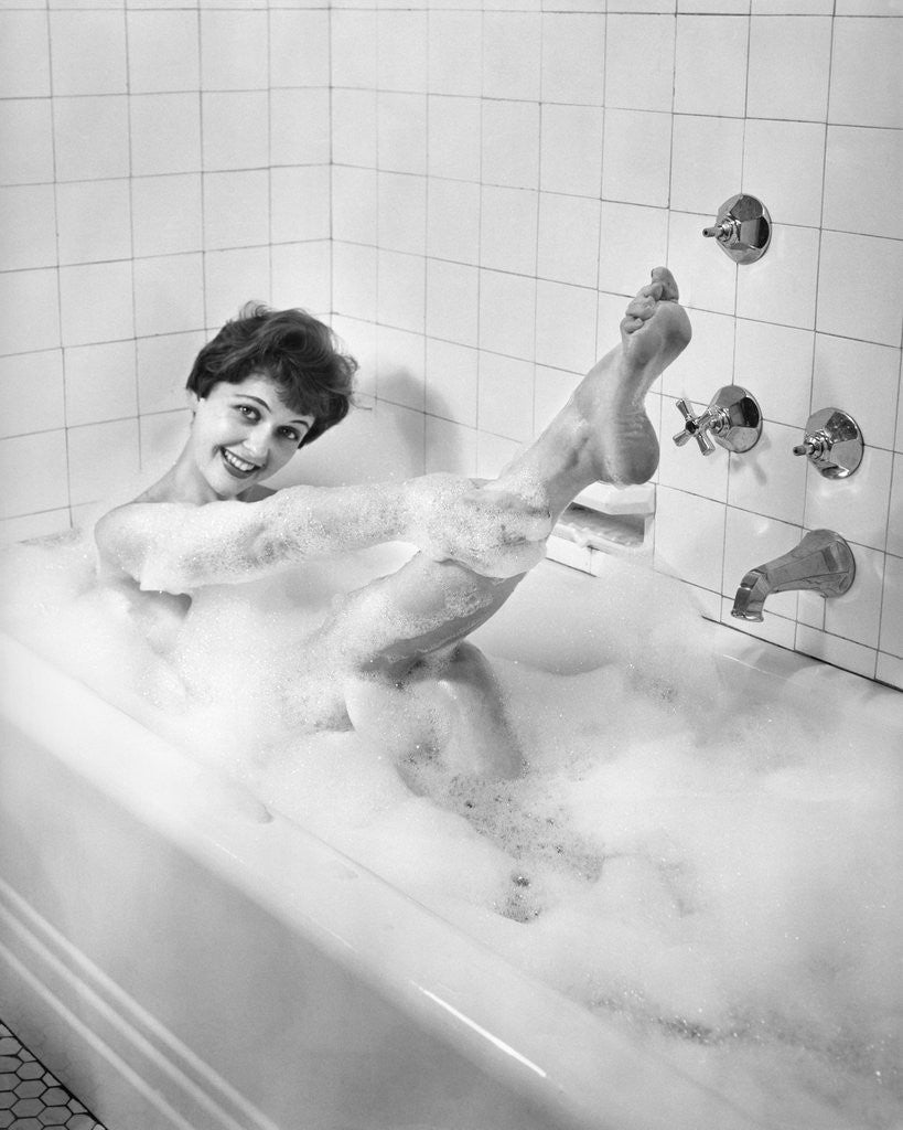 Detail of 1950s sexy smiling woman taking a soap suds bubble bath in tub looking at camera by Corbis