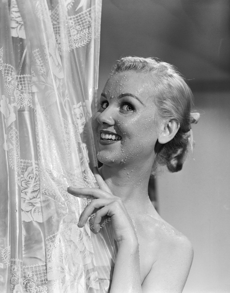 Detail of 1950s portrait of wet blonde peeking around shower curtain by Corbis