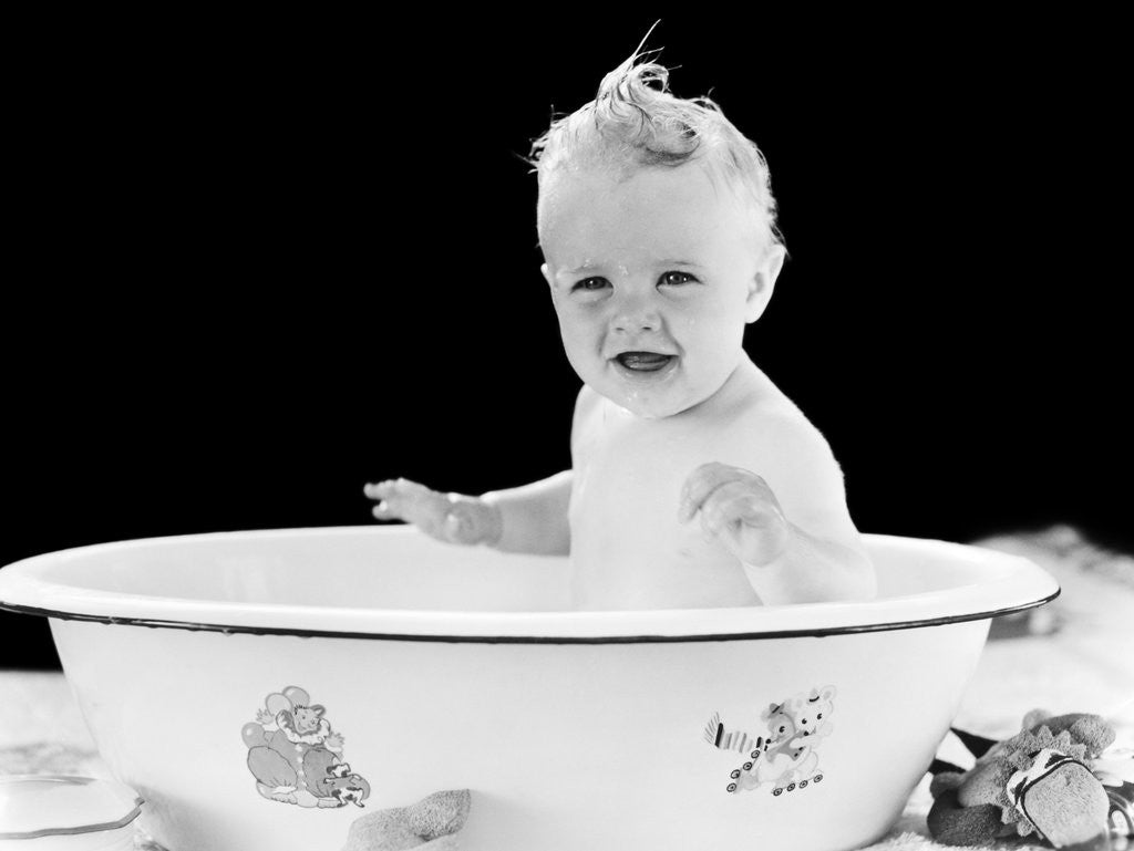 Detail of 1930s 1940s smiling happy baby sitting in enameled tin bathtub by Corbis